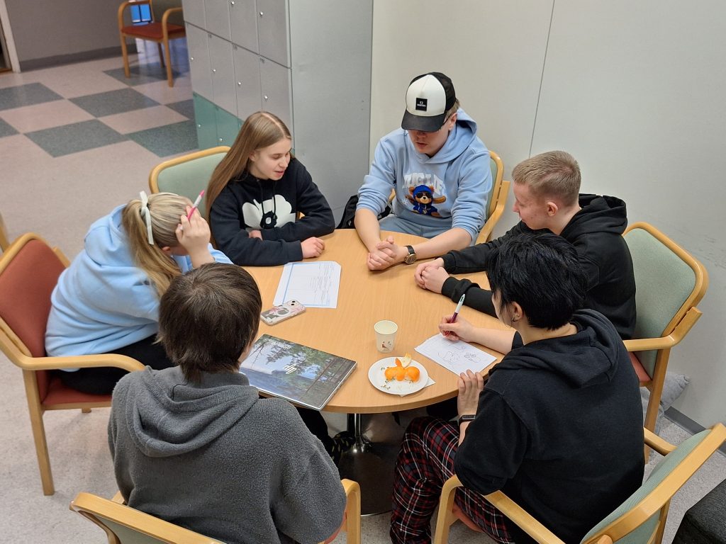 Lukiolaisten tiimi 6 suorittamassa yrittäjyyspäivän tehtävää pyöreän pöydän ääressä. 